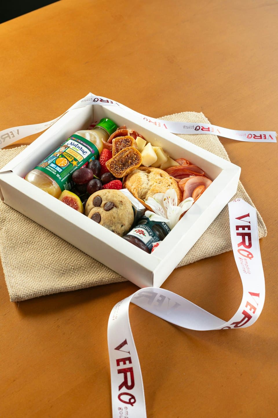 Gourmet gift box filled with food on a wooden table.