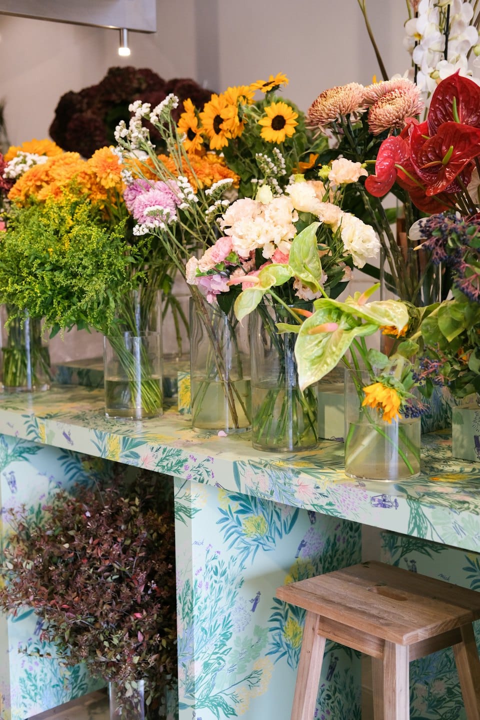 Fresh cut flowers in glass vases on a shop counter.